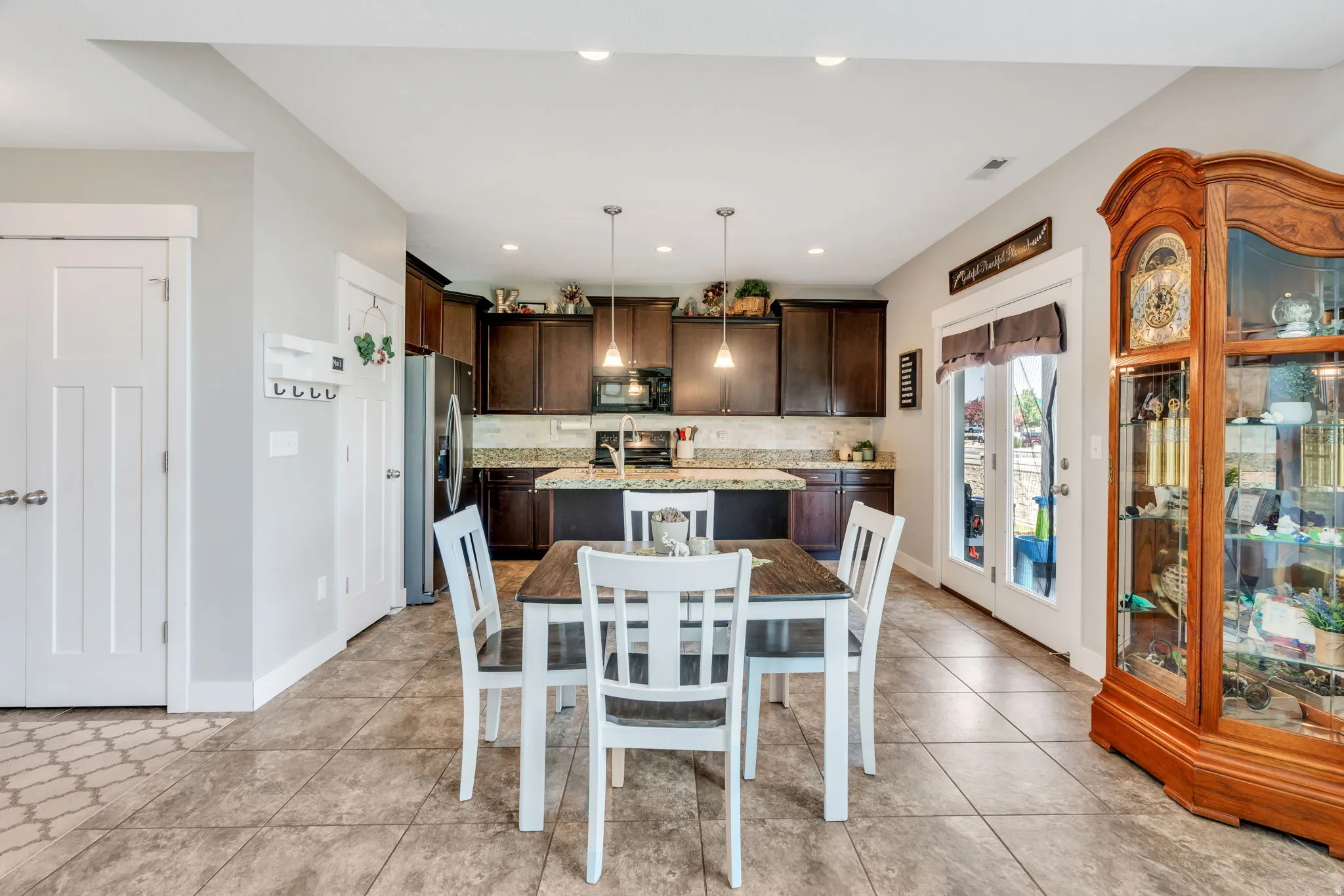 Open-concept kitchen and dining area featuring dark wood cabinetry, granite countertops, and a subway tile backsplash