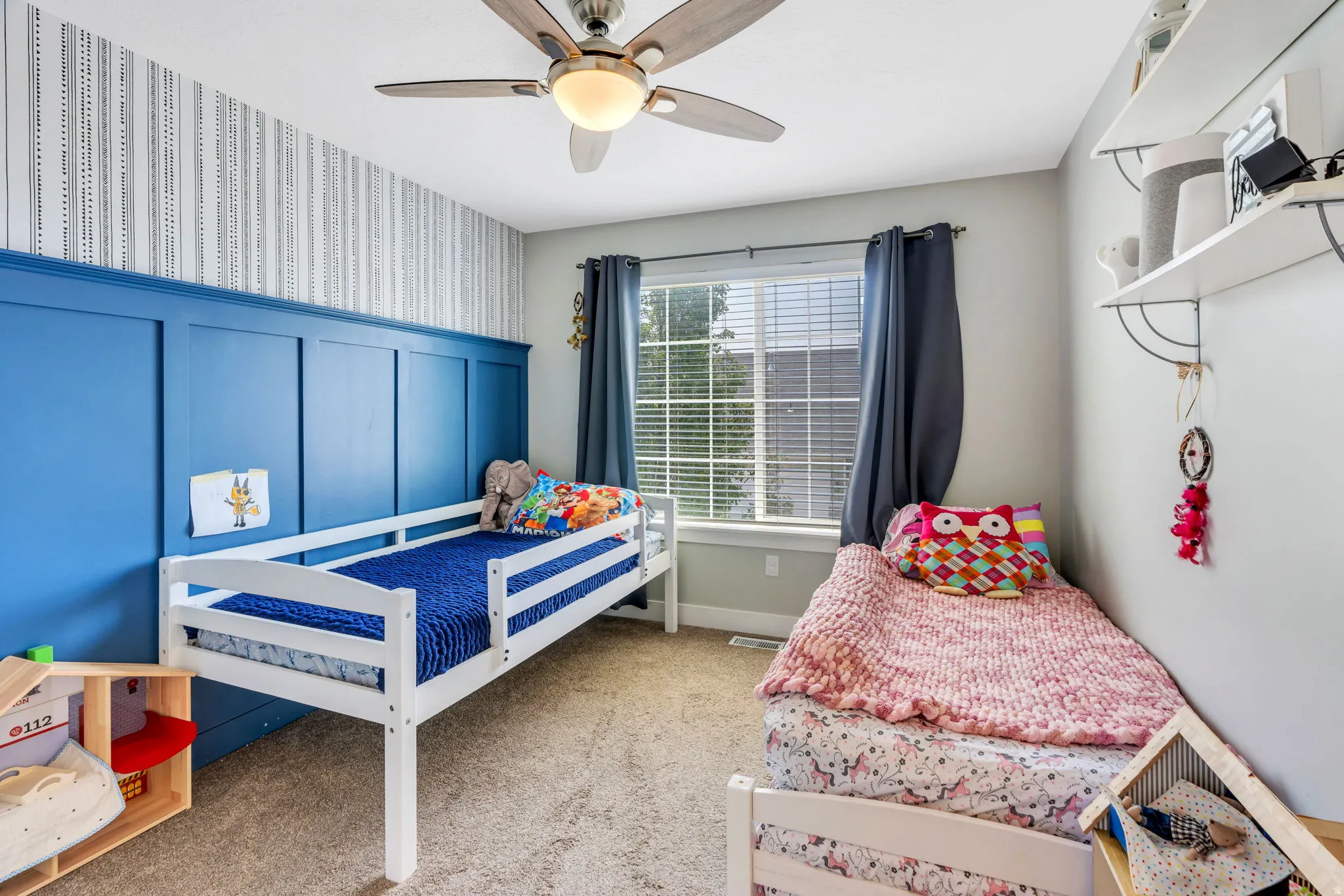 Interior room featuring a board and batten accent wall, neutral carpeting, a ceiling fan with light, and a window with blinds