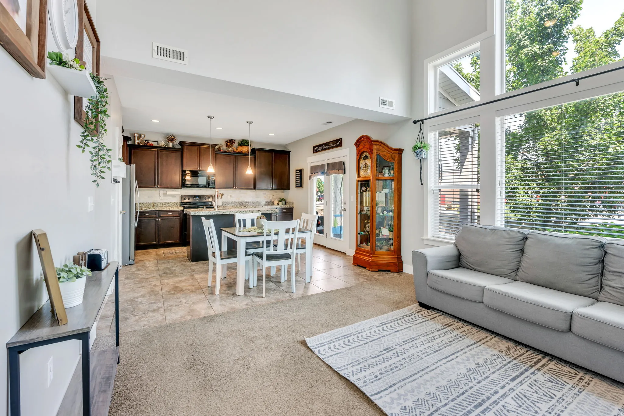 Open-concept living area featuring a kitchen with dark wood-finish cabinetry, light-toned countertops, and stainless steel appliances