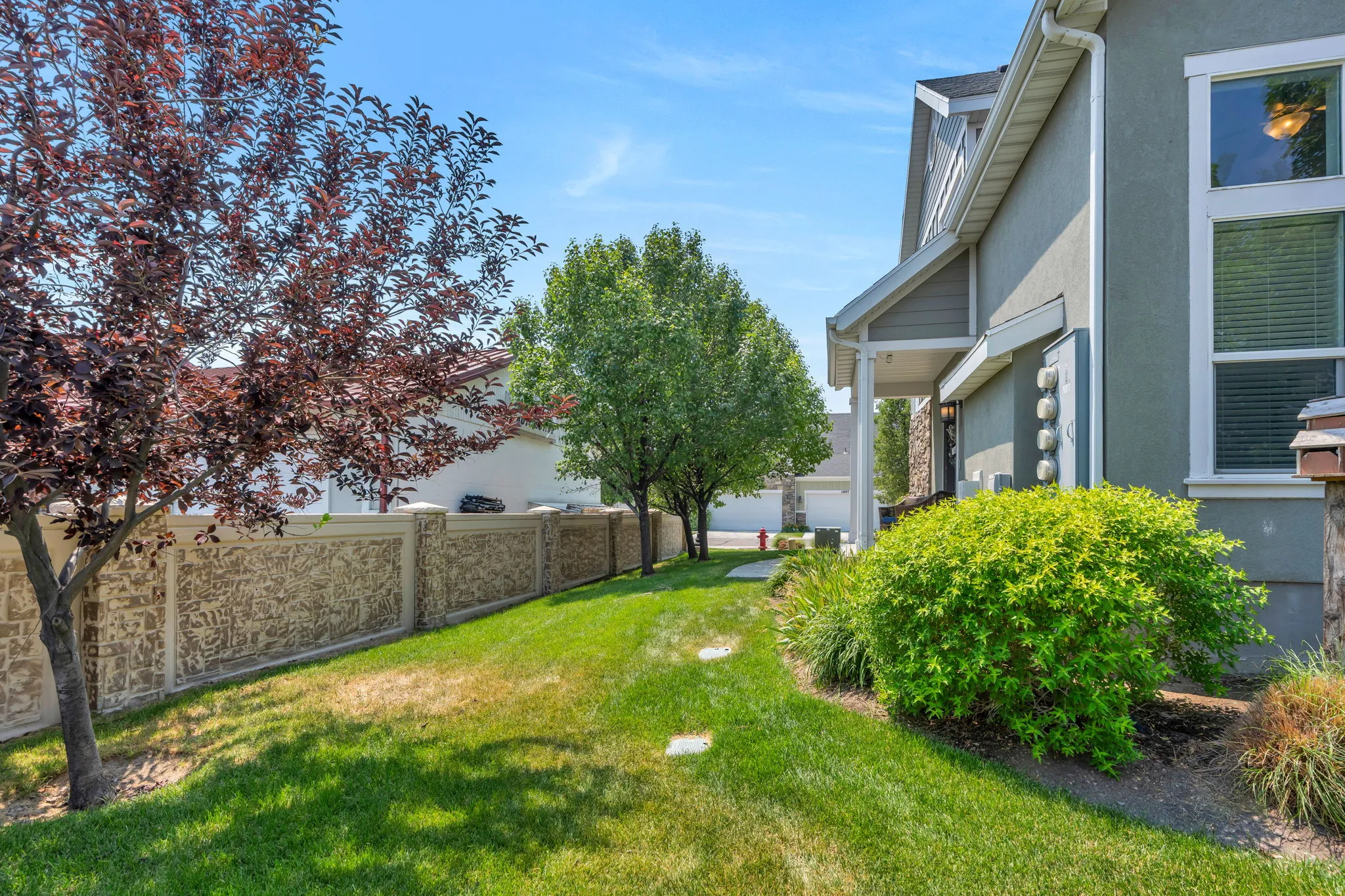 Manicured lawn with mature trees and a decorative stone perimeter wall
