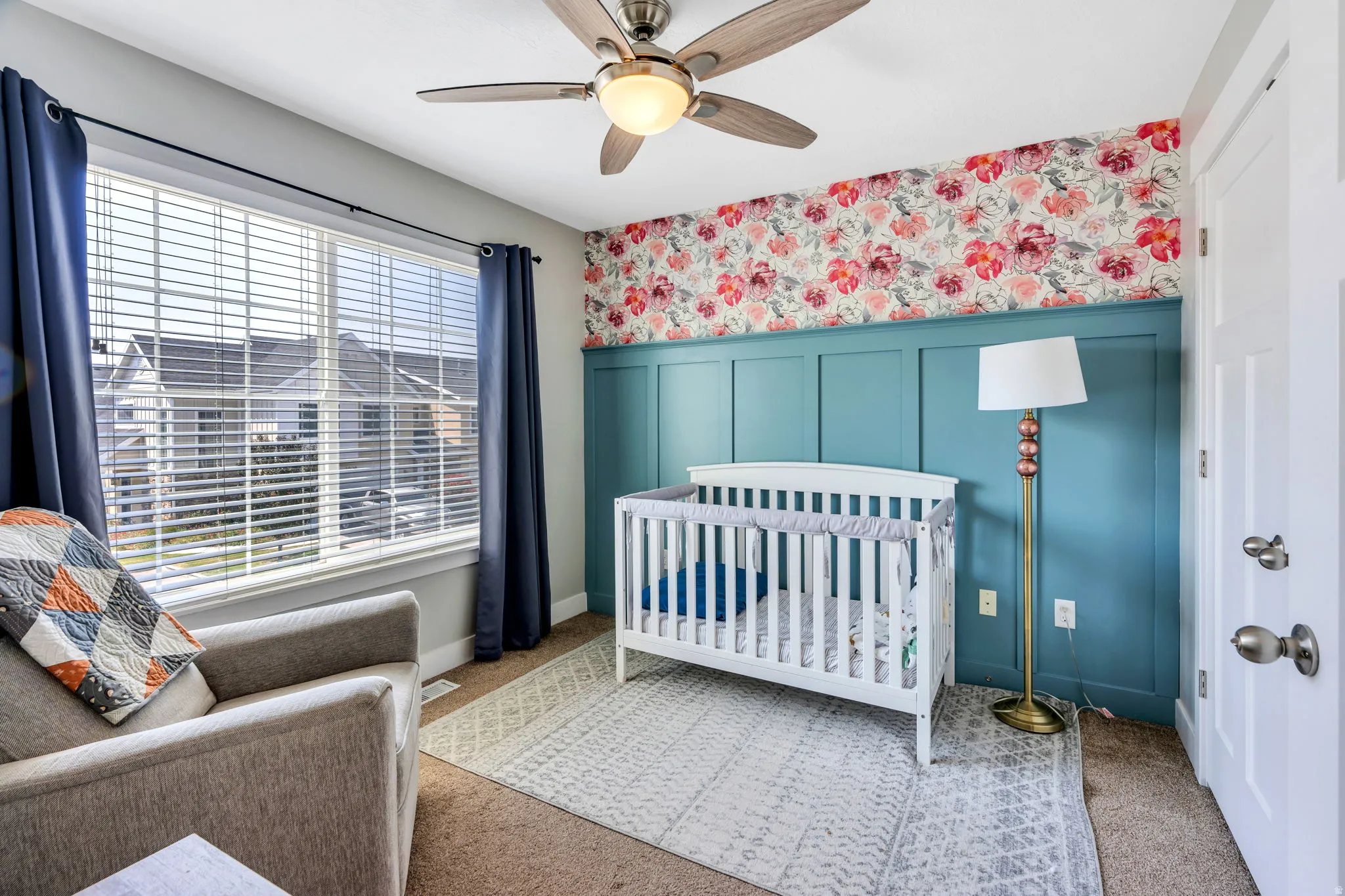 Bedroom featuring a ceiling fan with integrated lighting, a large window with blinds, and paneling with floral wallpaper