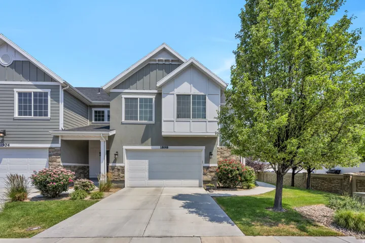Modern townhome exterior featuring a light gray stucco finish with stone accents and white trim