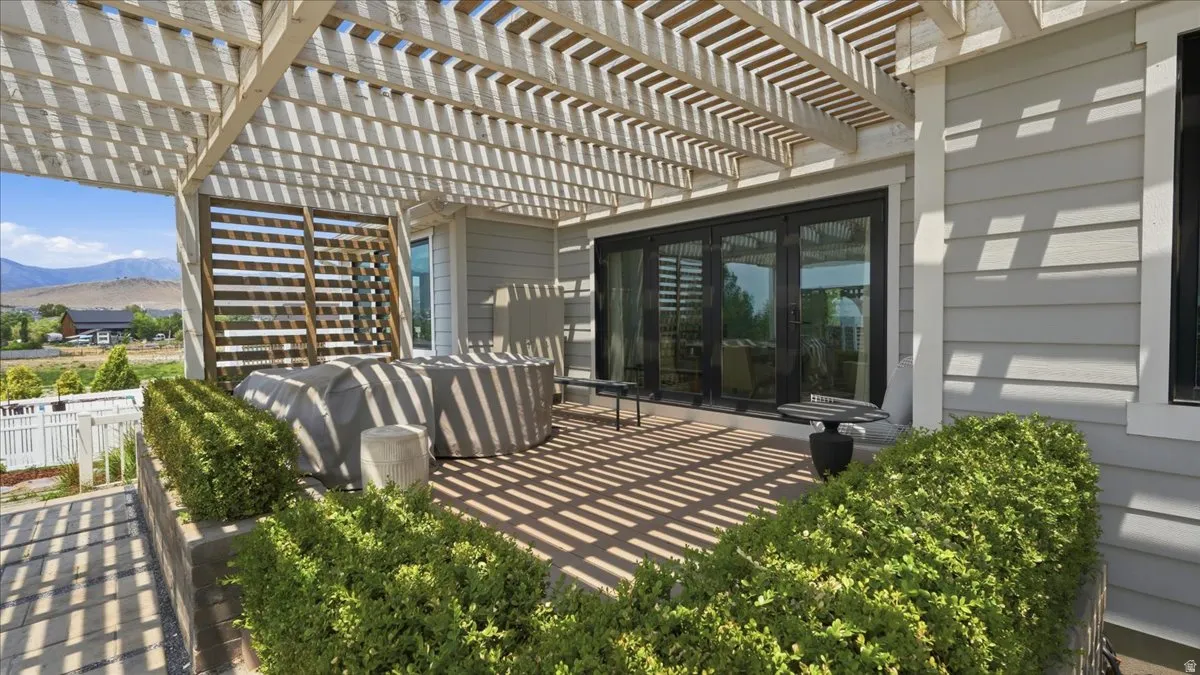 Expansive patio featuring a slatted pergola, composite decking, and mature landscaping