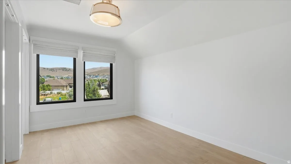 Spacious room featuring light wood-finish flooring, white walls, and a contemporary semi-flush mount ceiling fixture
