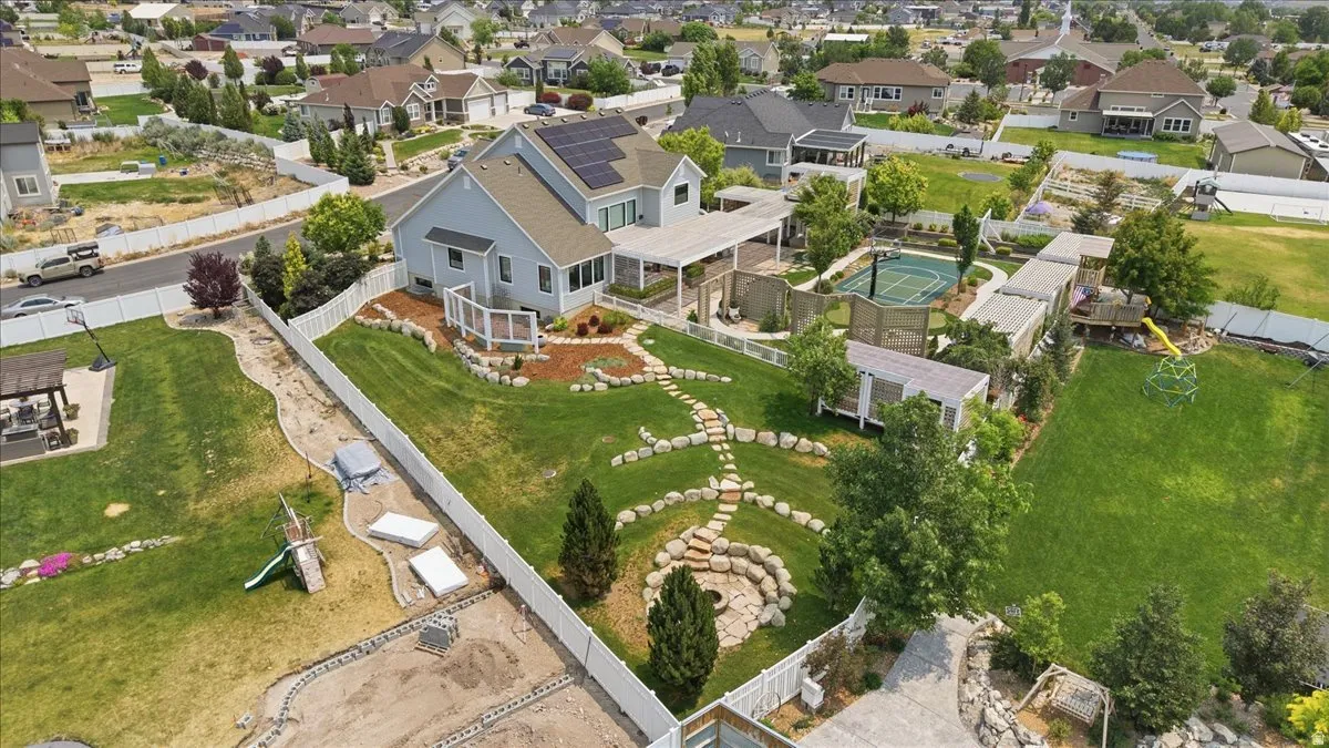 Expansive backyard featuring a stone pathway, a dedicated sports court, a pergola-covered patio, and a fire pit area