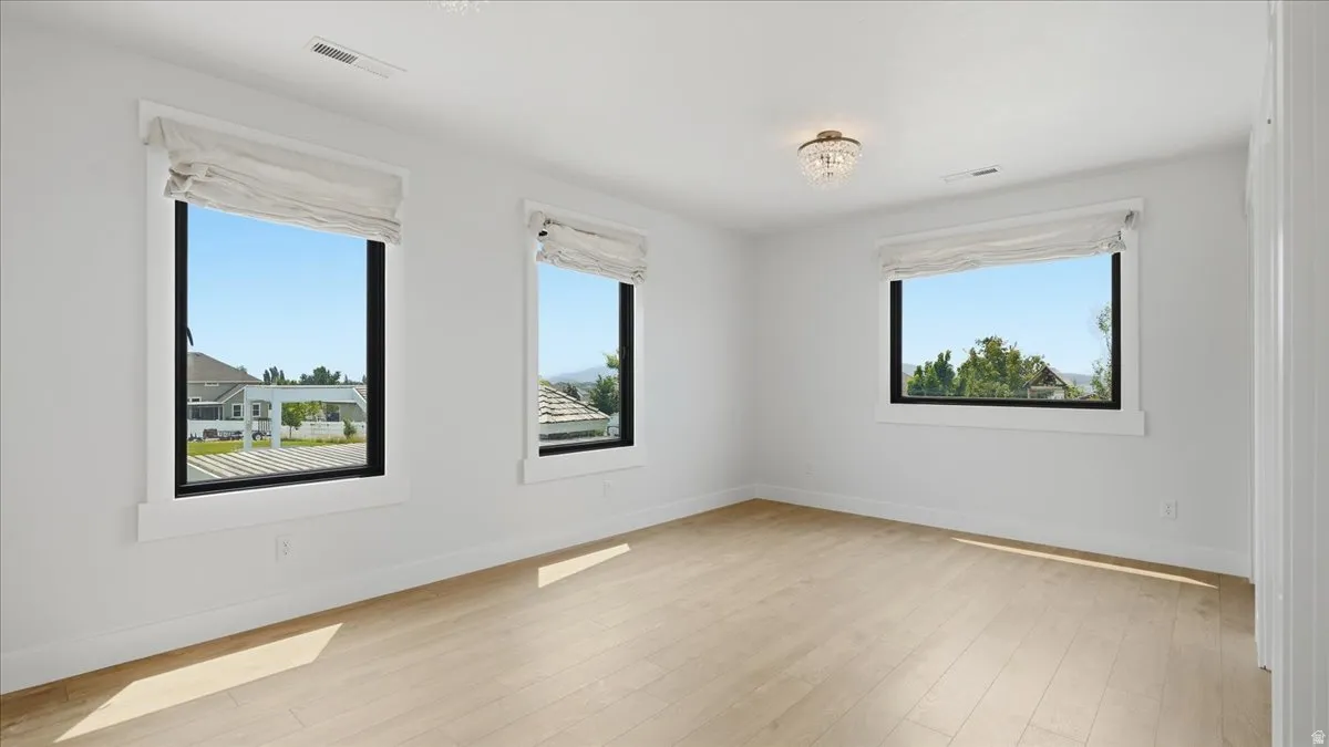 Bright room featuring light wood-finish flooring, white walls, and a recessed ceiling light