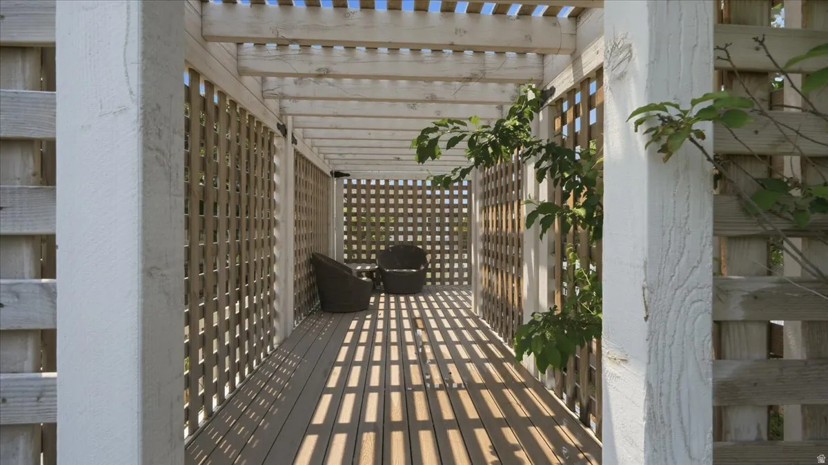 Pergola-covered walkway featuring a slatted roof, lattice side panels, and composite decking
