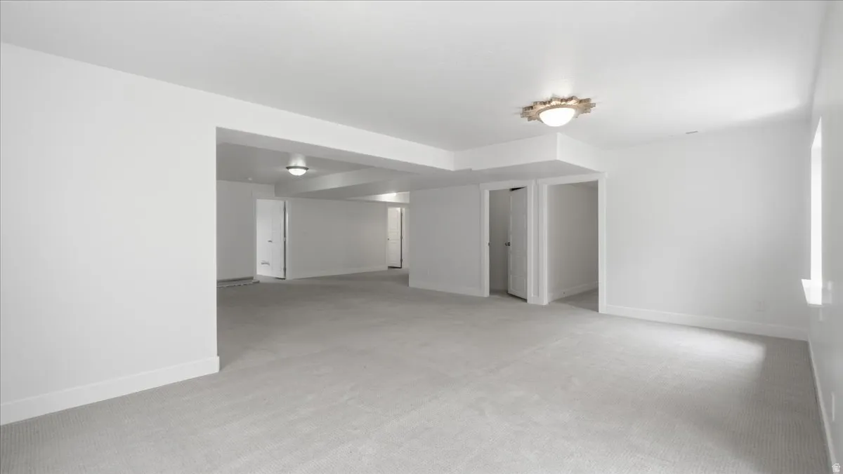 Spacious room featuring light gray carpeting, white walls, white trim, and recessed lighting