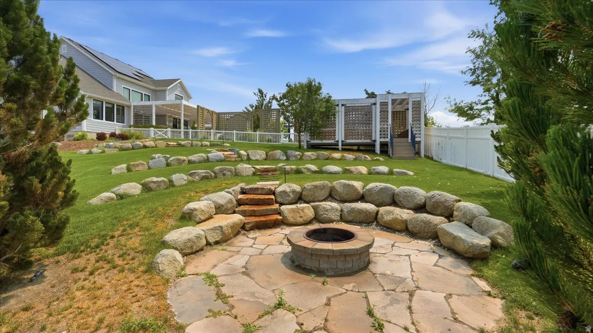 Expansive terraced backyard featuring a flagstone patio with a built-in fire pit, natural stone retaining walls, and a multi-level lawn
