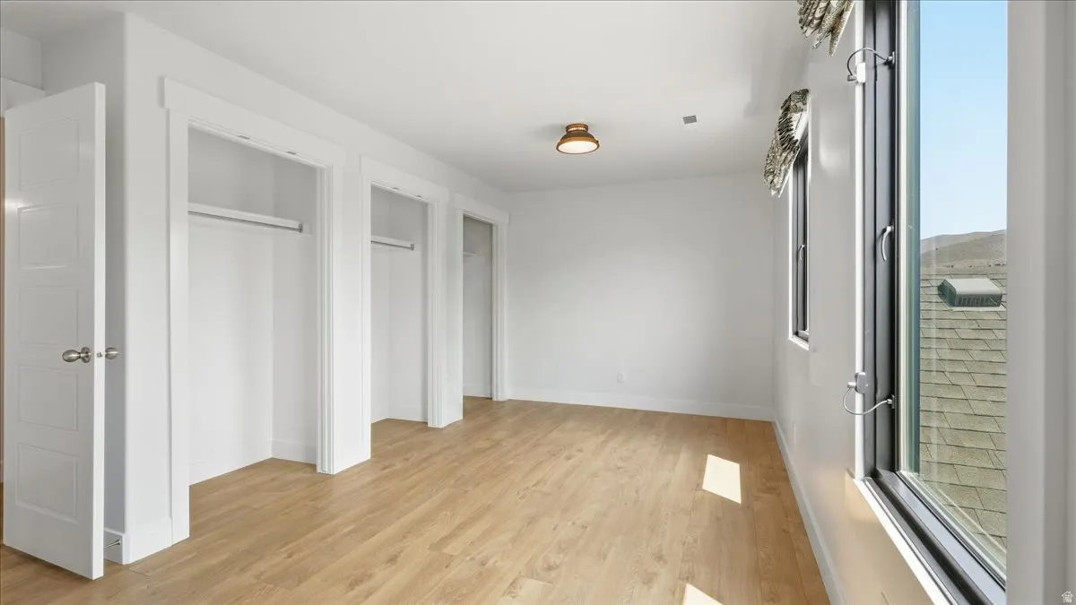 Bright room with wood-finish flooring, multiple closet spaces, and large windows