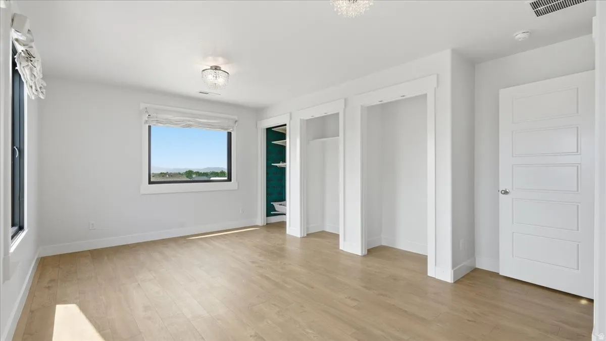 Bright interior space featuring light wood-finish flooring, white walls, and a large window with a distant landscape