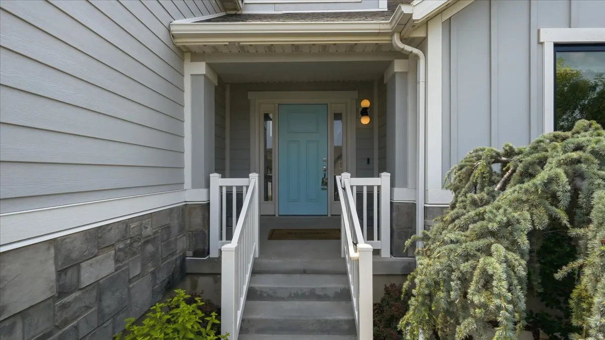 Inviting entryway featuring a light blue door, concrete steps with white railings, and a covered porch