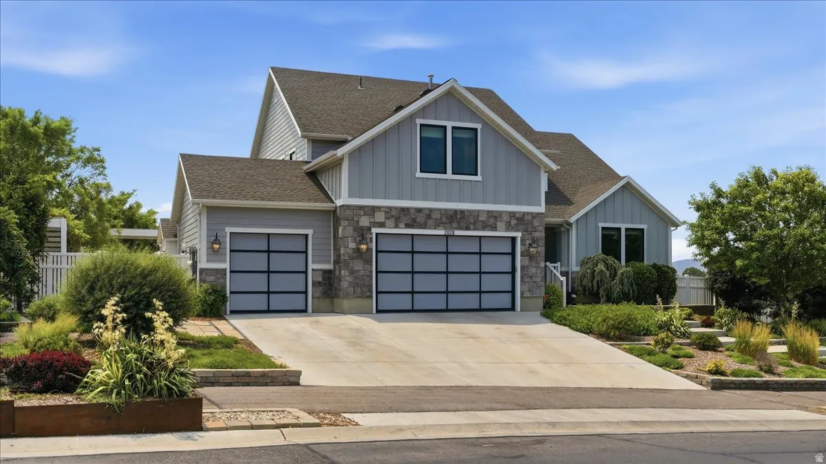 Modern split-level residence featuring light gray siding and stone accents