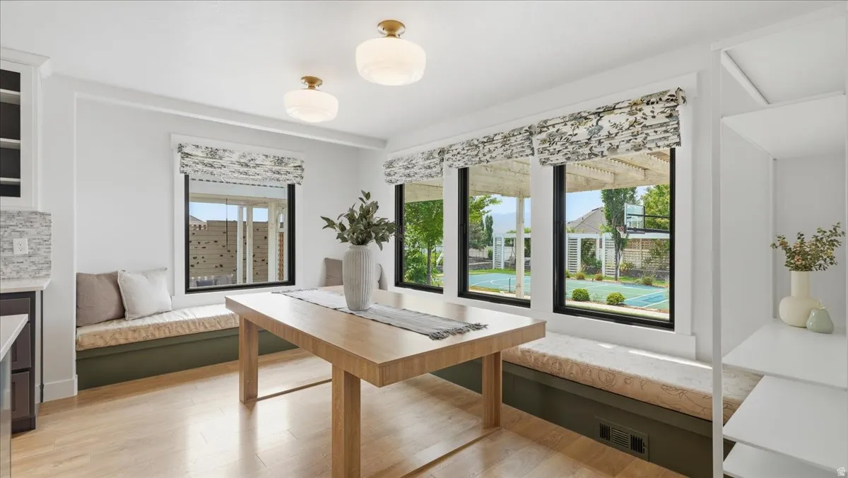 Bright dining area featuring wood-finish flooring, two window seats with upholstered cushions, and built-in shelving