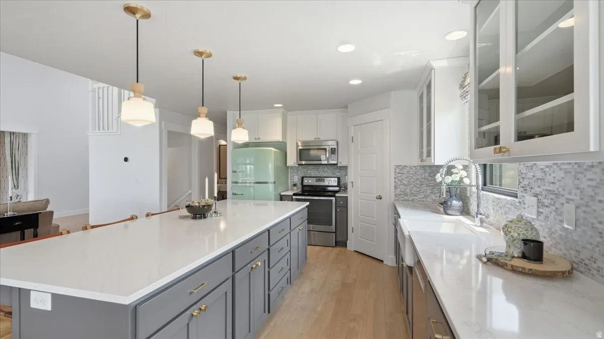 Kitchen featuring a large central island with seating, pendant lighting, quartz countertops, and wood-finish flooring