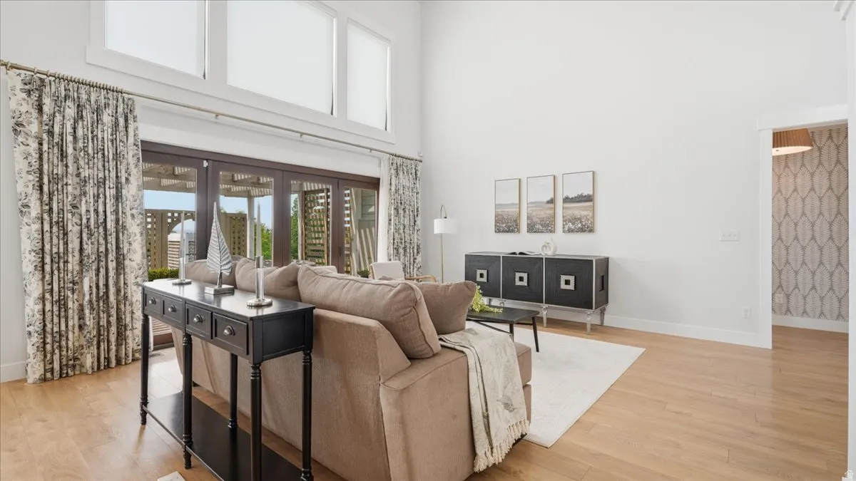 Spacious living area featuring high ceilings, wood-finish flooring, and large multi-pane windows