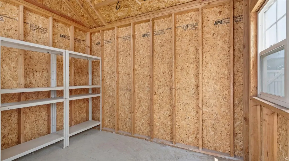 Storage shed interior with exposed wood framing, oriented strand board walls, and concrete flooring