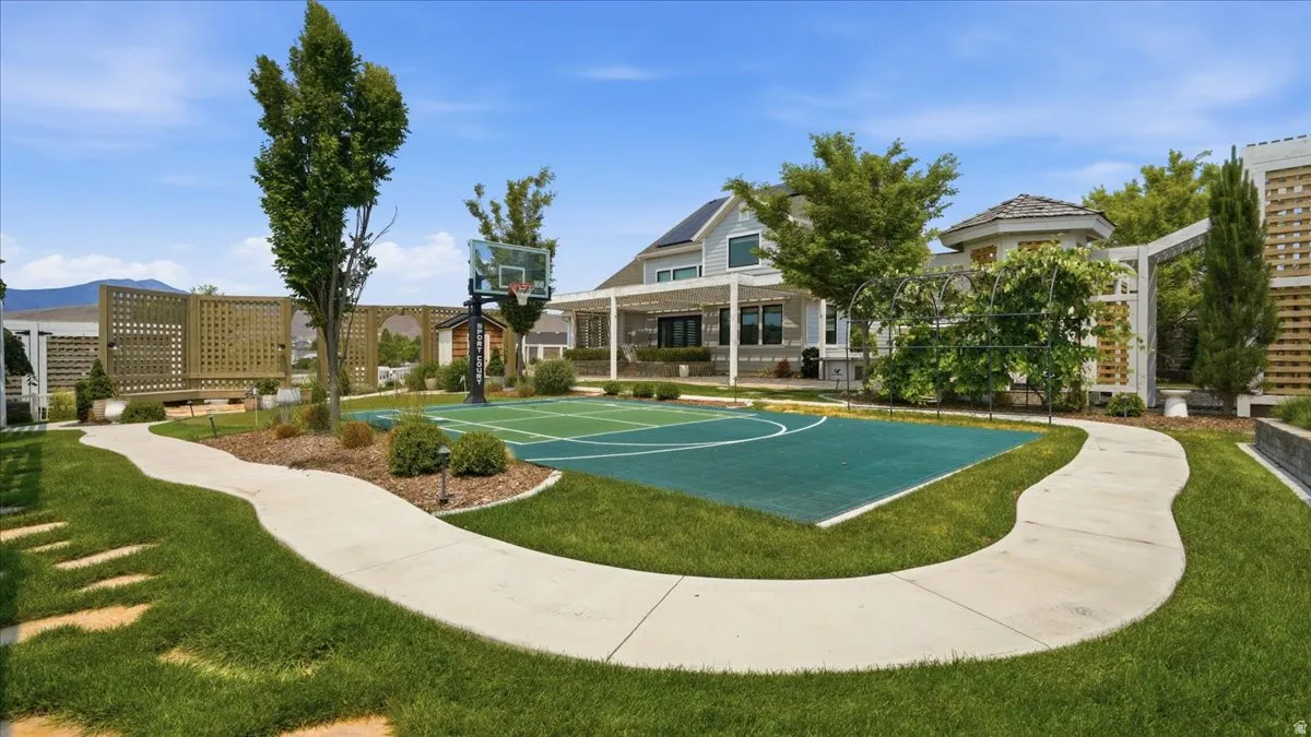 Outdoor sports court with painted game lines, surrounded by manicured lawn and mature landscaping