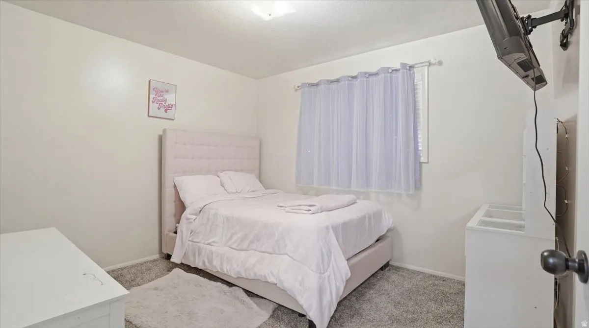 Bedroom featuring white walls, gray carpet, and a window with blinds