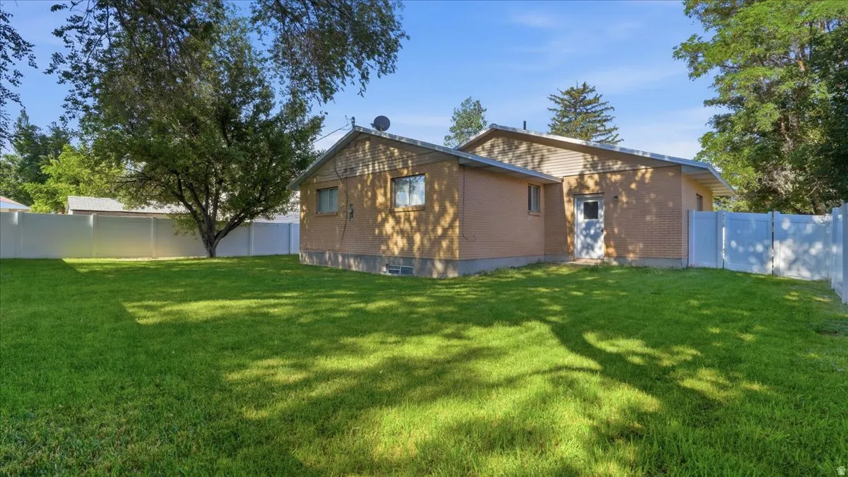 Expansive green lawn with mature trees and a white privacy fence encompassing the property