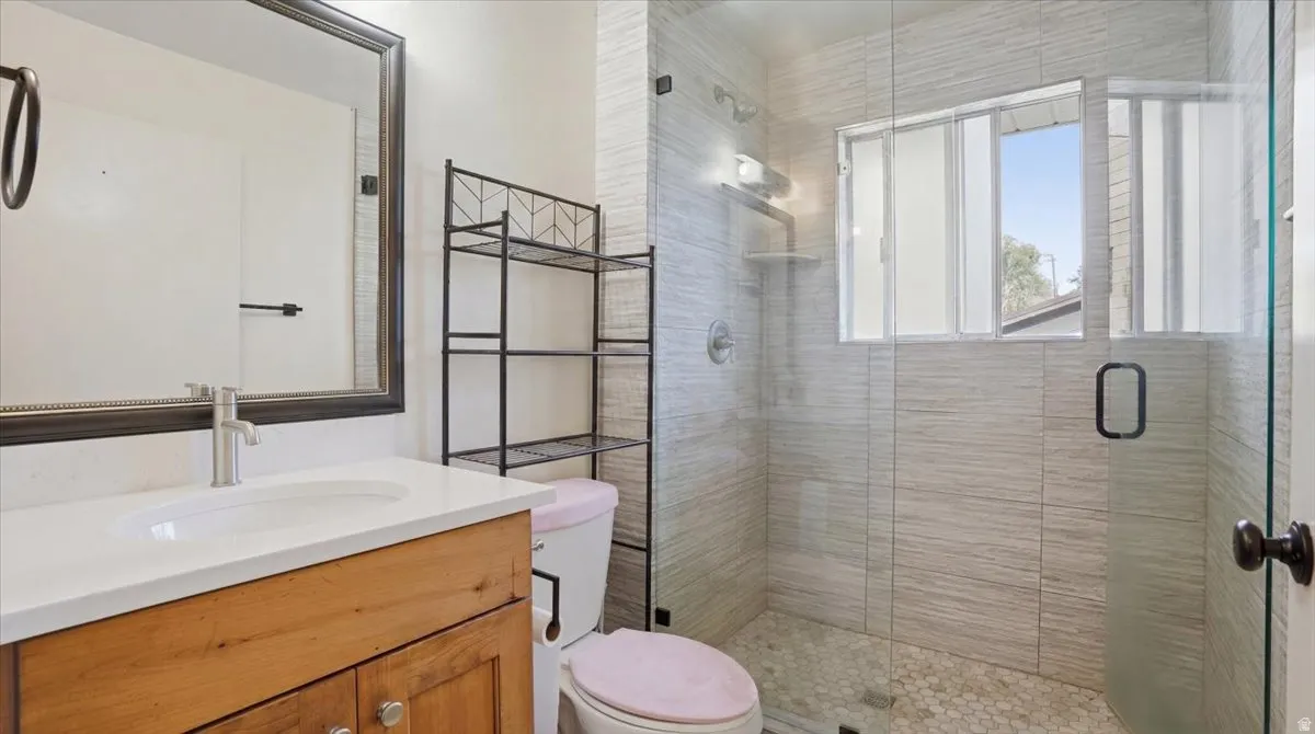 Modern bathroom with a glass-enclosed shower featuring light-toned tile walls and a pebble-style floor