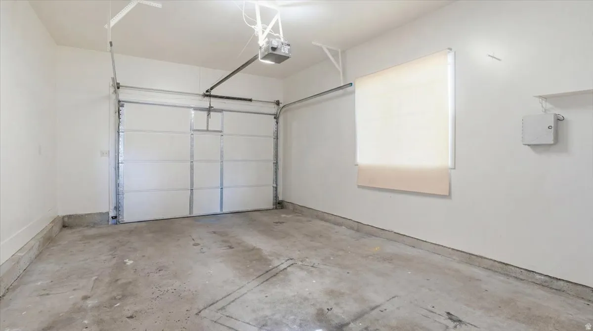 Spacious garage with a concrete floor, white walls, and an automatic overhead door