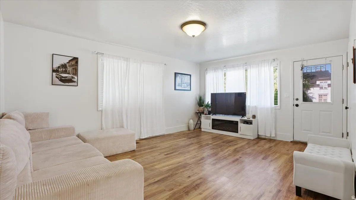 Bright living area featuring wood-finish flooring, white walls, and a ceiling-mounted light fixture