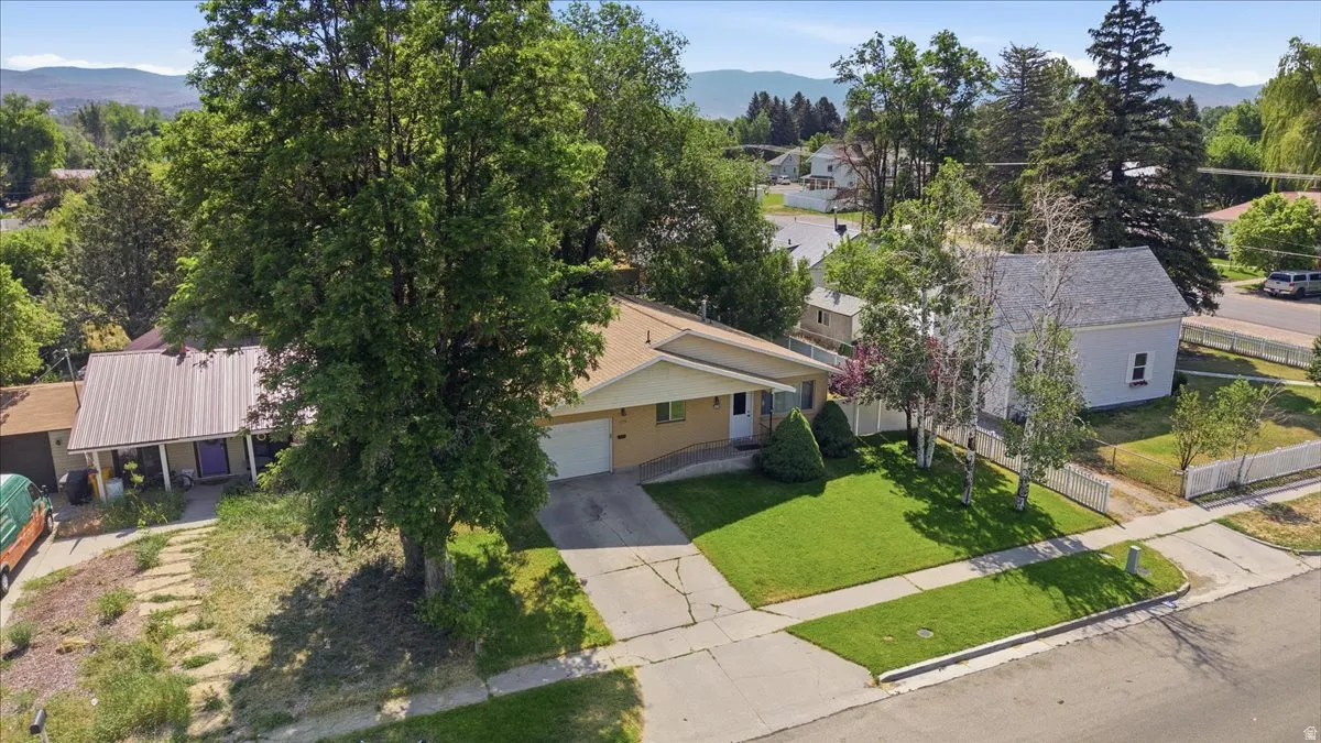Single-story residence featuring an attached garage, paved driveway, and established front lawn