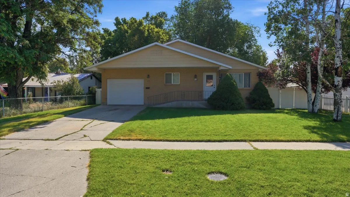 Single-story residence featuring a front lawn, attached garage, and a concrete driveway