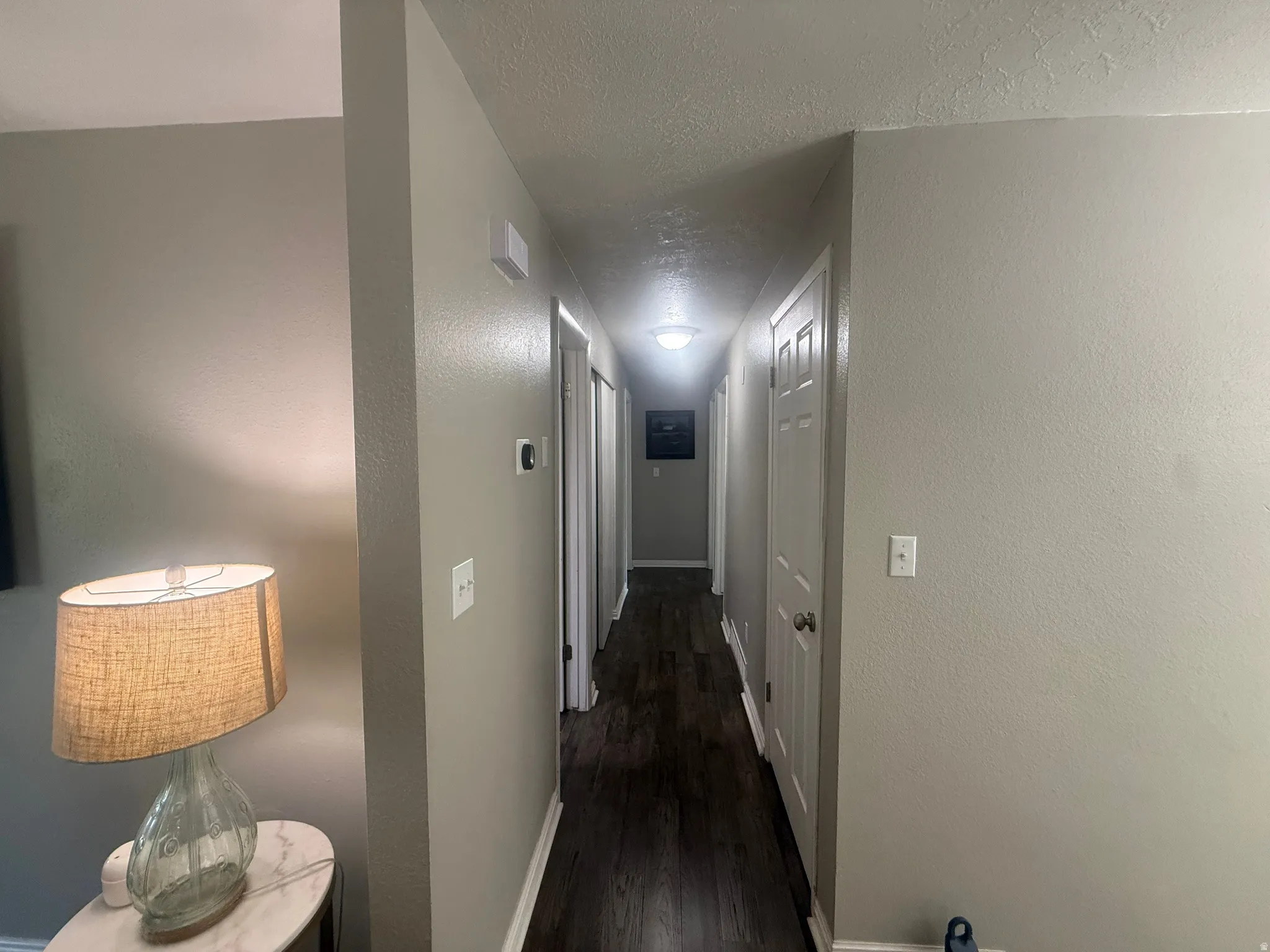 Long hallway with wood-finish flooring, light grey painted walls, and white trim