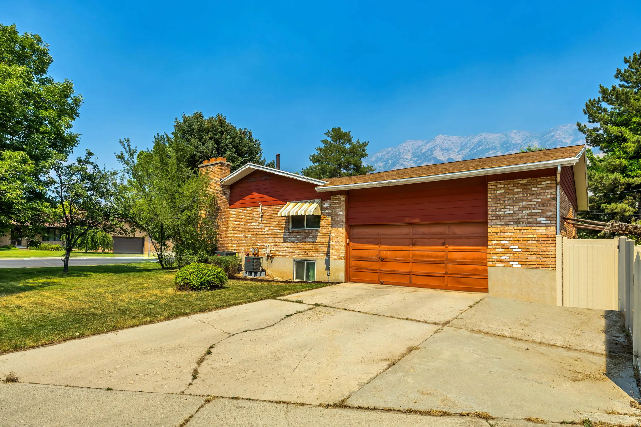 Exterior featuring a wood-panel garage door, brick and wood siding, and an awning over a window