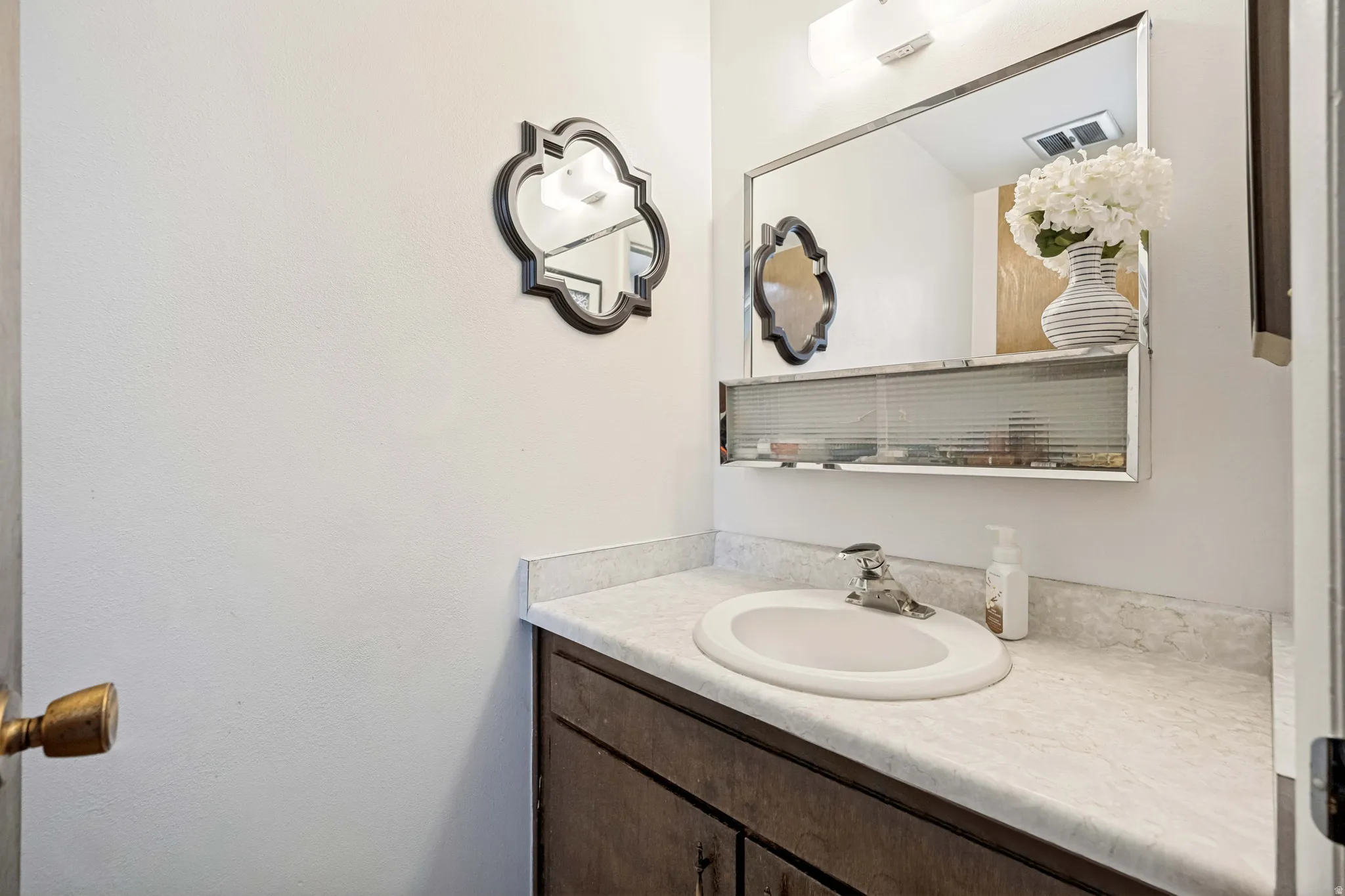 Bathroom vanity featuring a built-in sink, durable countertop, and wood-finish cabinetry
