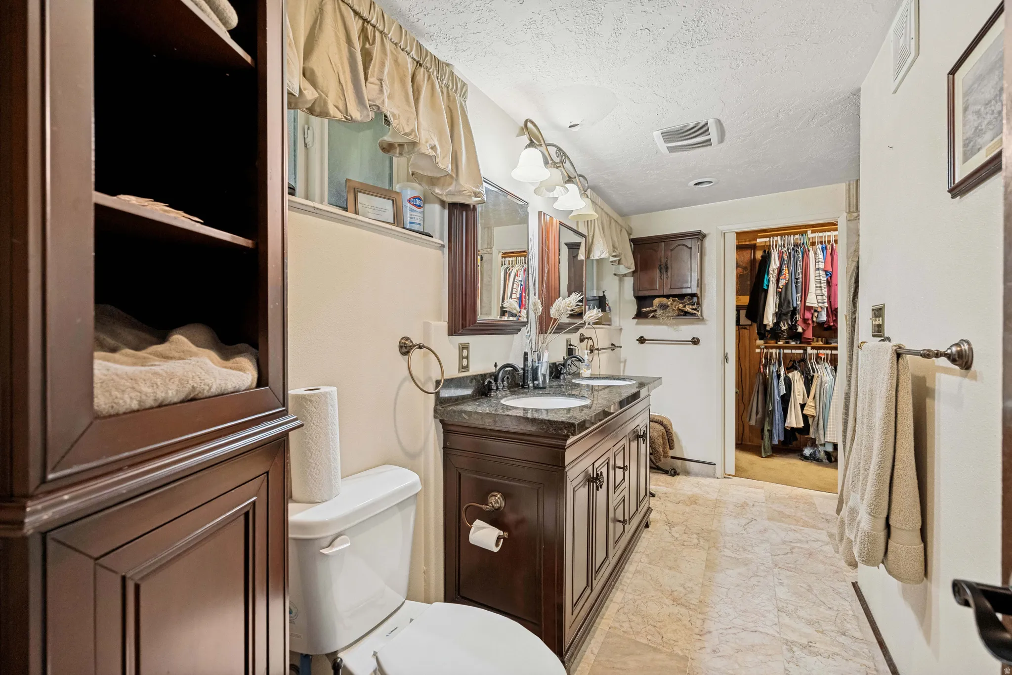 Bathroom featuring a double vanity with dark wood cabinetry and a stone countertop