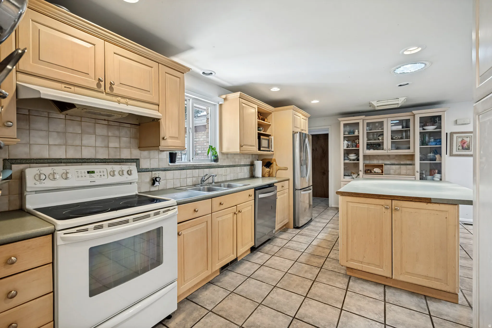 Kitchen featuring wood cabinetry, tile flooring, recessed lighting, a built-in oven range, and a central island with countertop space