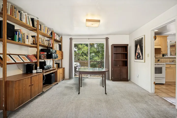 Room featuring light-toned carpeting and a sliding glass door leading to an outdoor deck
