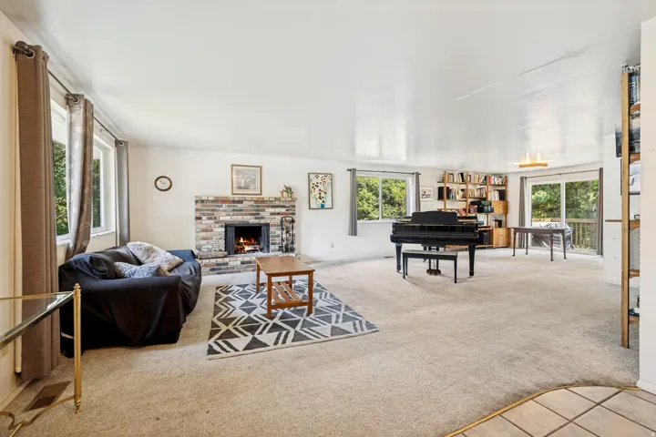 Spacious living area featuring a brick fireplace, light-toned carpeting, and multiple windows