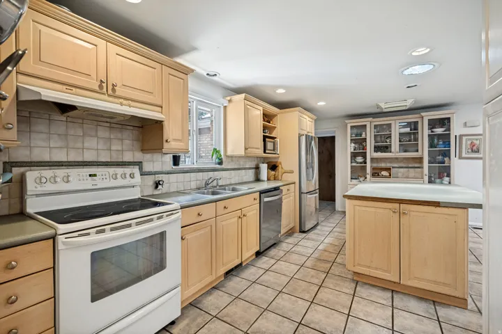 Kitchen featuring wood cabinetry, tile flooring, recessed lighting, a built-in oven range, and a central island with countertop space