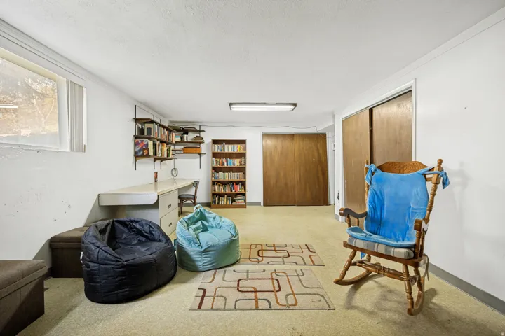 Lower-level room with a built-in desk, shelving, a bookshelf, and dual sliding wood doors