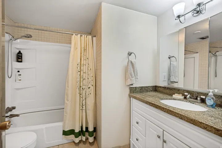 Bathroom featuring a white vanity with silver hardware, an integrated oval sink, and a speckled countertop