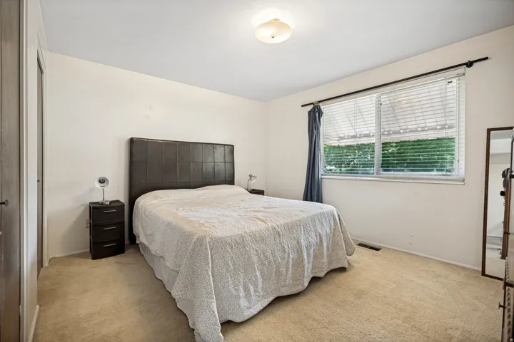 Bedroom featuring neutral wall paint, ceiling-mounted light fixture, carpeting, and a window with horizontal blinds and drapery rod