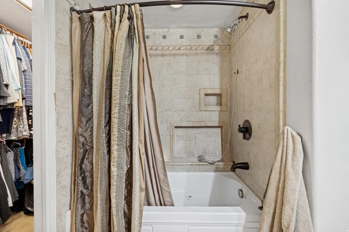 Bathtub with tiled surround featuring mosaic accents and built-in niches, oil-rubbed bronze fixtures, and a curved shower rod