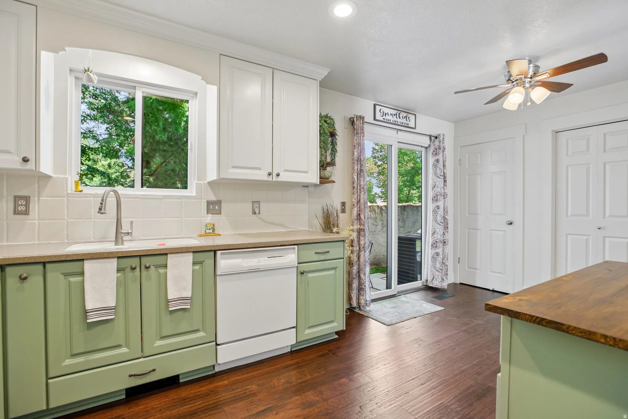 Kitchen featuring two-tone cabinetry with white upper and green lower cabinets, a white tile backsplash, and a contemporary stainless steel faucet