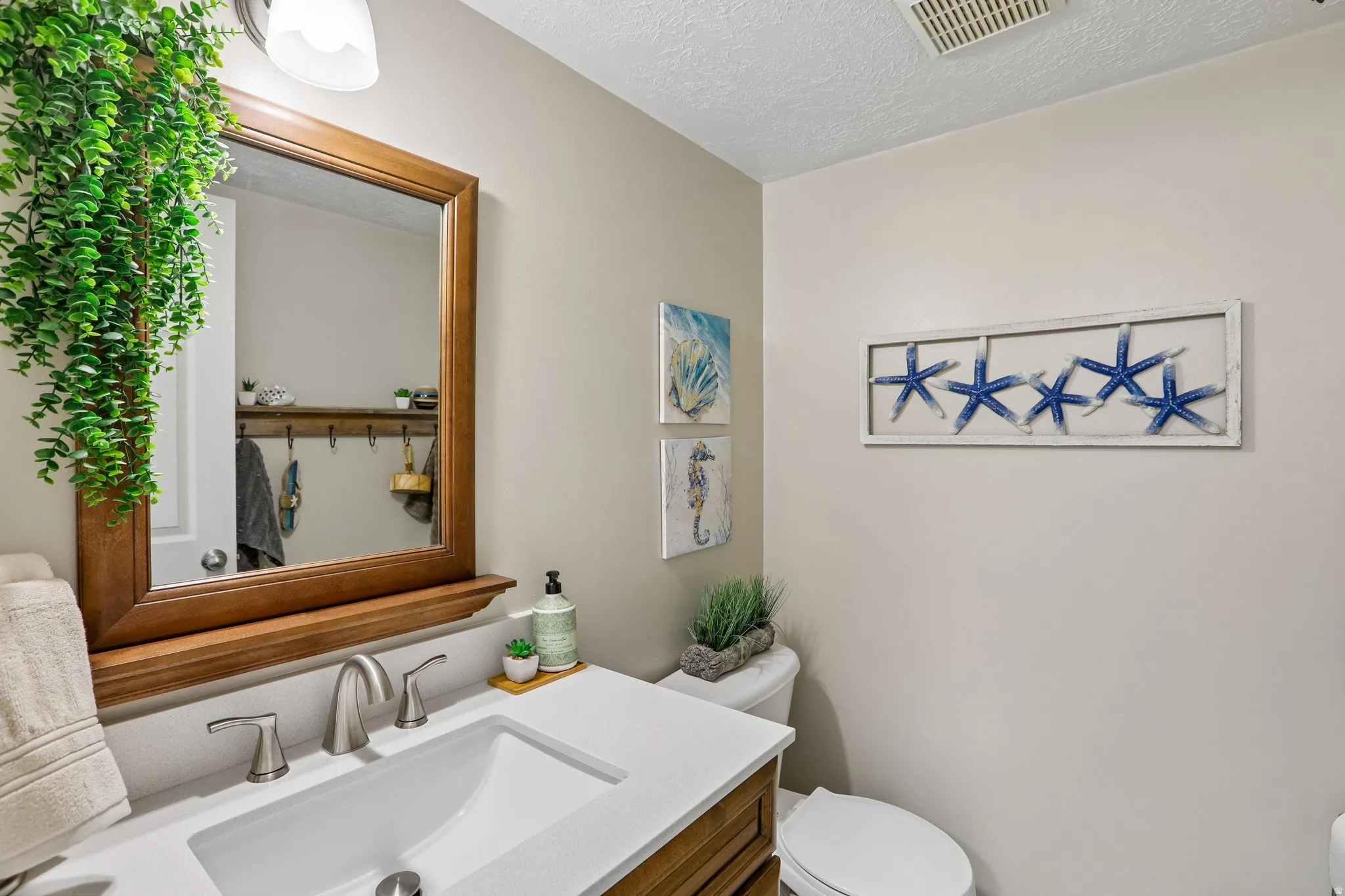 Bathroom featuring a wood-framed mirror with an integrated shelf, a white rectangular sink, and a brushed nickel faucet set