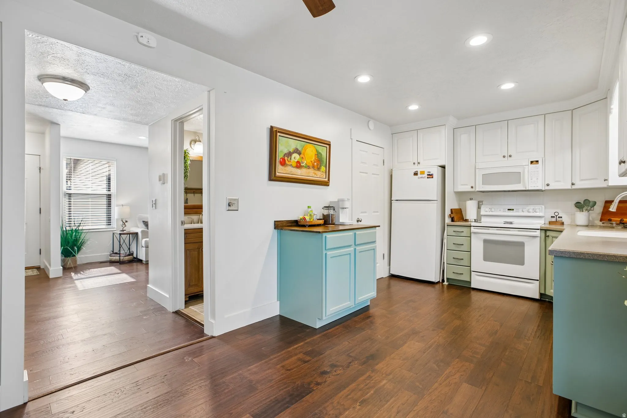 Kitchen featuring wood-finish flooring, white cabinetry, a built-in microwave, and recessed lighting