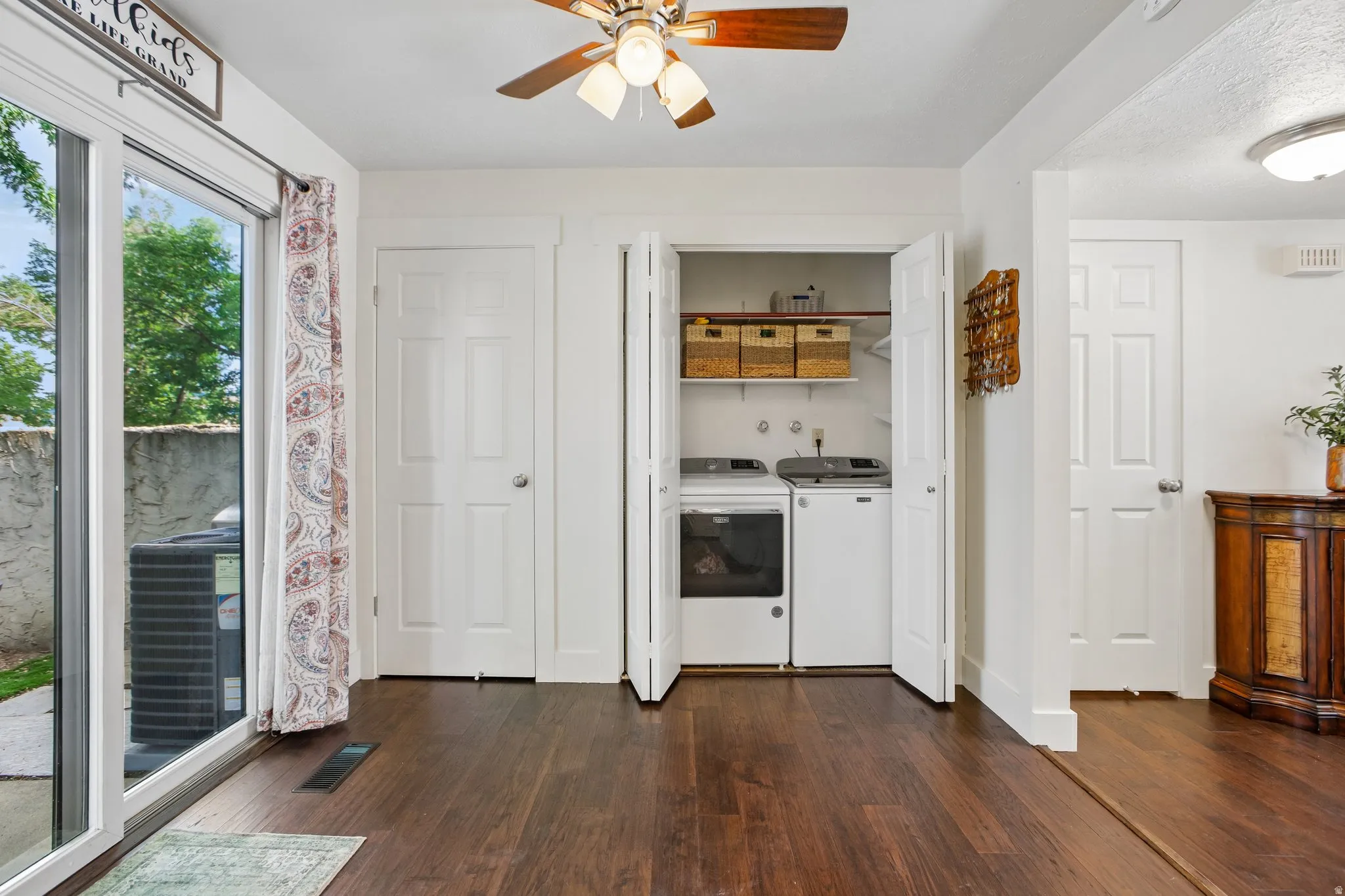 Dedicated laundry closet with built-in shelving, wood-finish flooring, white paneled doors, and a ceiling fan with light fixture