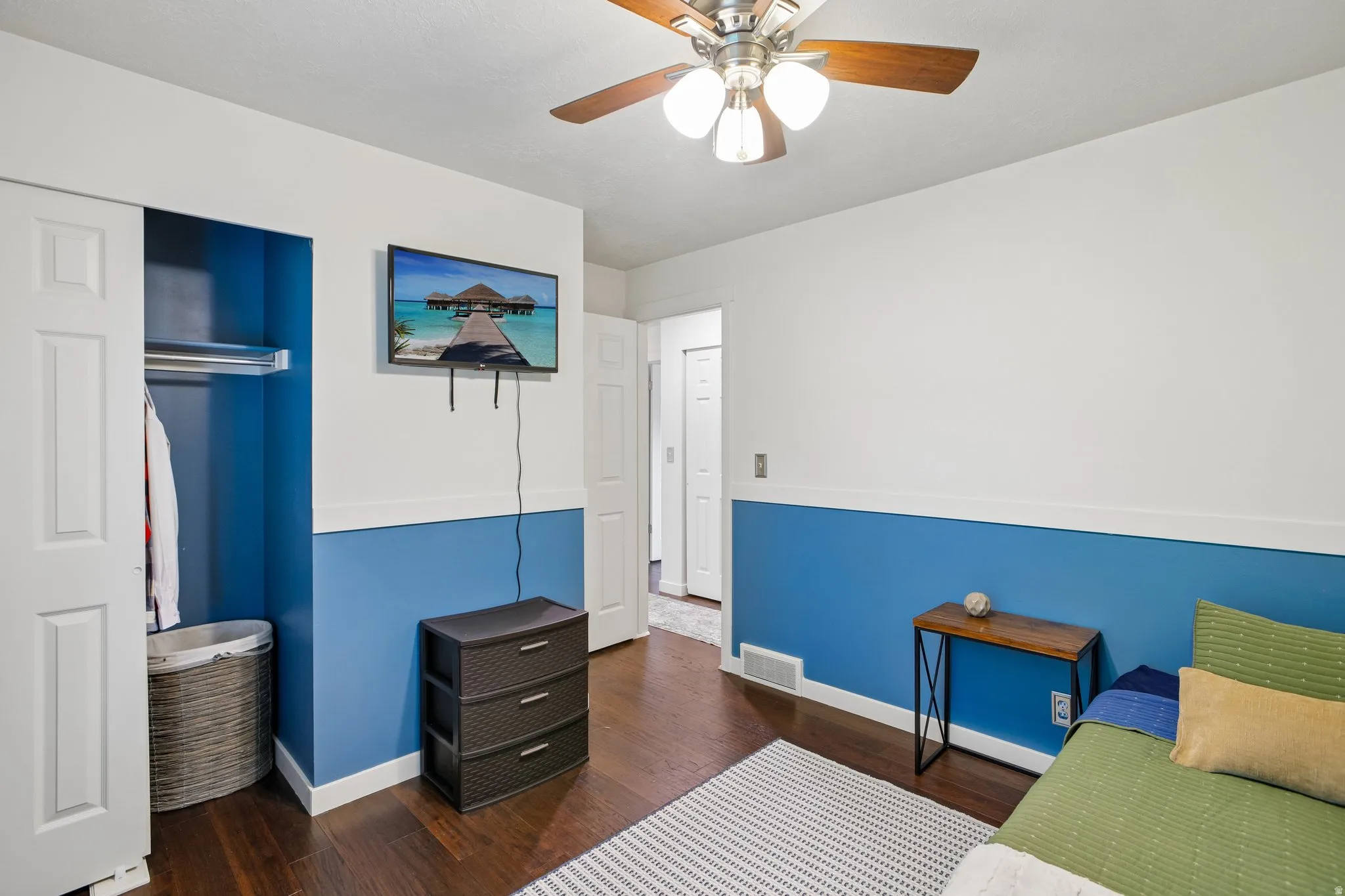 Interior room featuring wood-finish flooring, two-tone wall paint, and a ceiling fan with integrated lighting