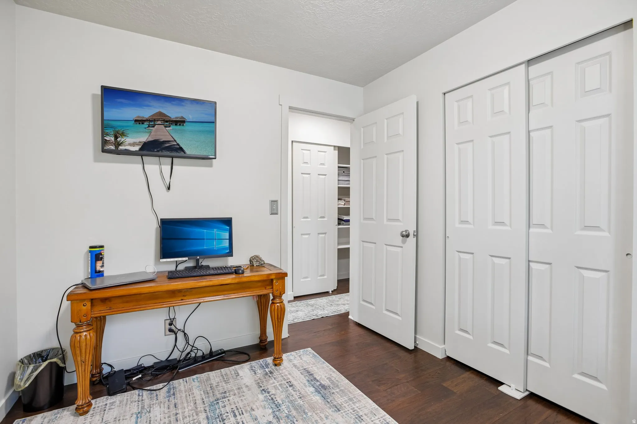 Room featuring dark wood-finish flooring, white walls, and bright overhead lighting