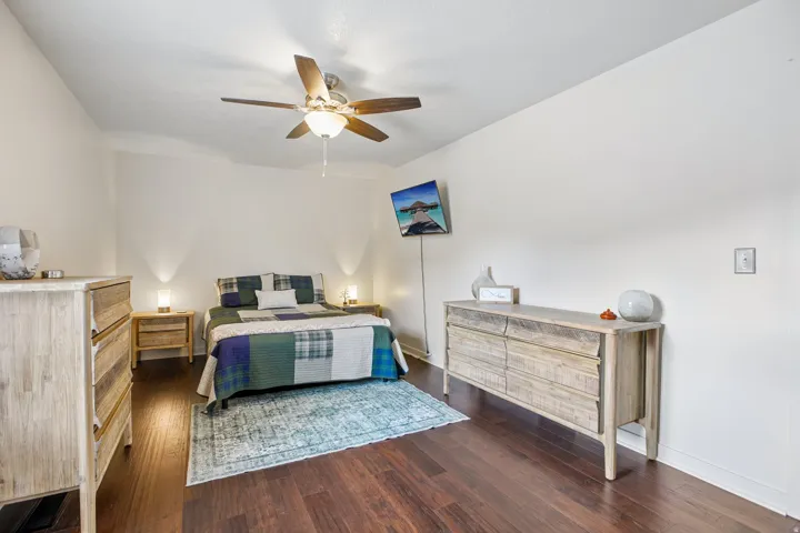 Spacious room featuring rich wood-finish flooring, a ceiling fan with integrated lighting, and neutral wall tones