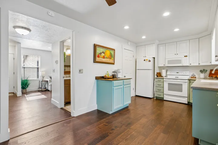 Kitchen featuring wood-finish flooring, white cabinetry, a built-in microwave, and recessed lighting