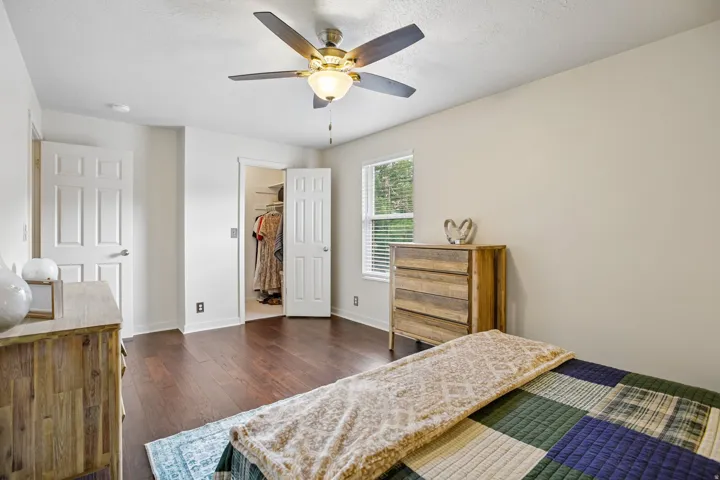 Bedroom featuring wood-finish flooring, a ceiling fan with integrated lighting, and neutral wall tones